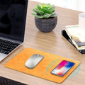 Brown leather desk mouse pad with integrated wireless charging for mobile phones.