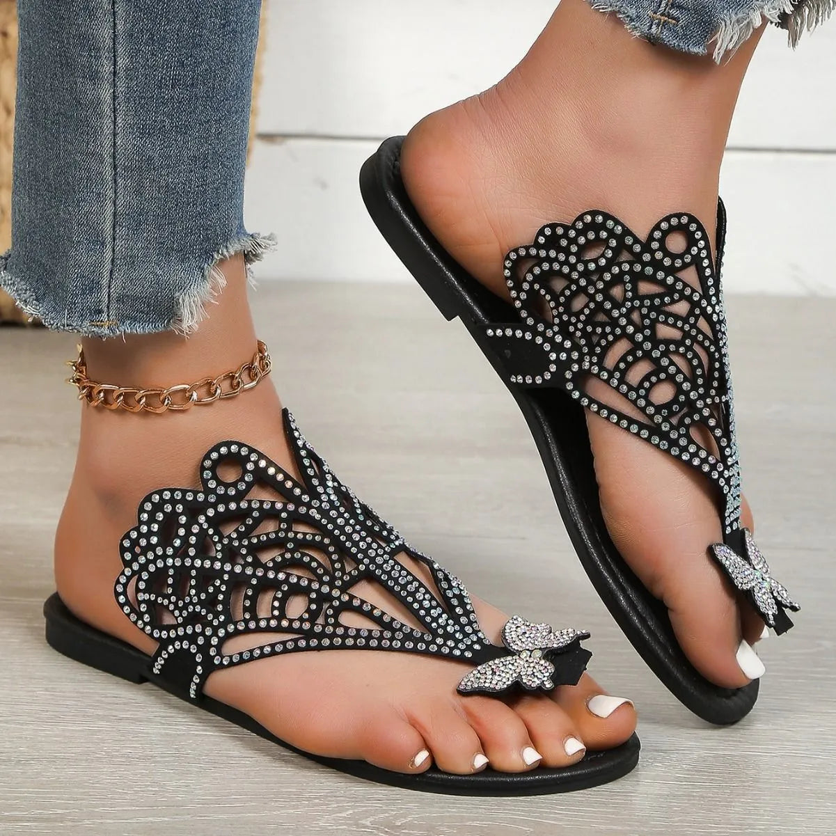 Women's black slip-on sandals with rhinestone detail, flip-toe design, and flat rubber sole.