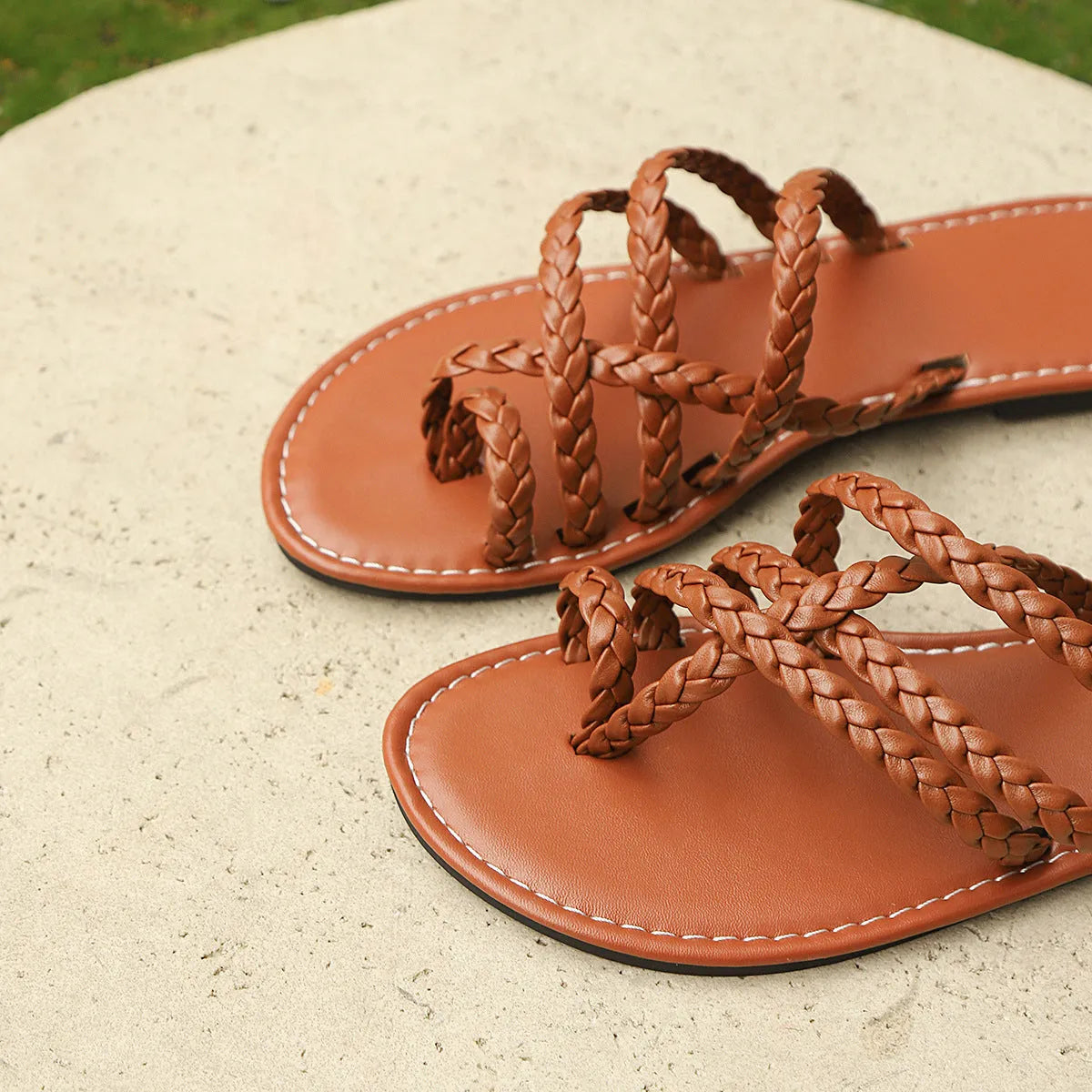 Women's flat woven sandals with a clip-toe design in white, shown on a foot.