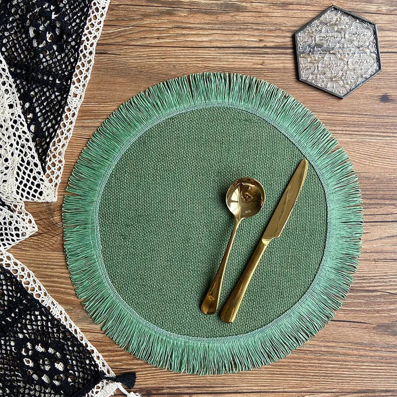 Handwoven round jute placemat with tassel edge in original hemp colour on a wooden table