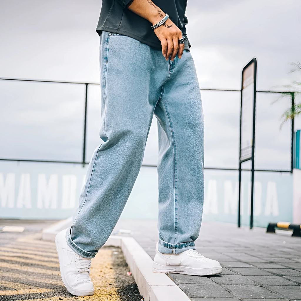Man wearing dark blue loose straight-leg casual jeans with a mid-waist and zipper fly.
