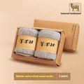 Two pairs of thick, solid-colour winter wool socks in a box, shown in khaki and dark grey.