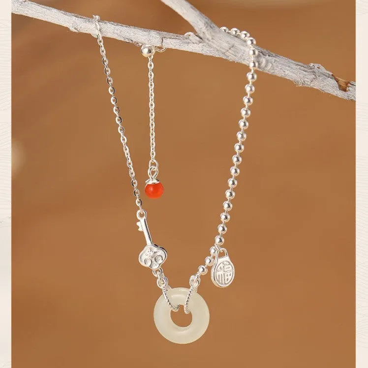 Women's Chinese style silver bracelet with a Hetian jade stone and intricate Peace Buckle design.