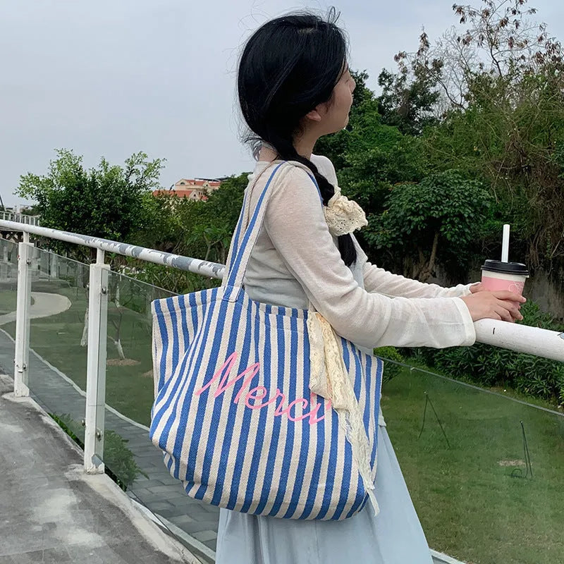 Pink cotton canvas bag with a printed design of blue and white striped letters.