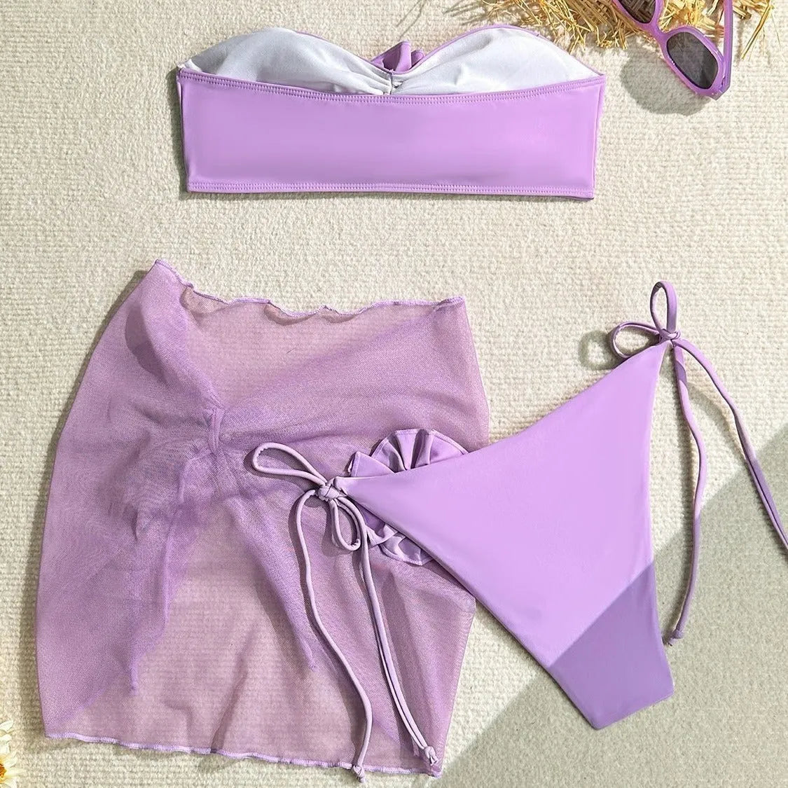 Women's pink tube top swimsuit with large 3D flower tie, matching pants, and skirt laid flat.