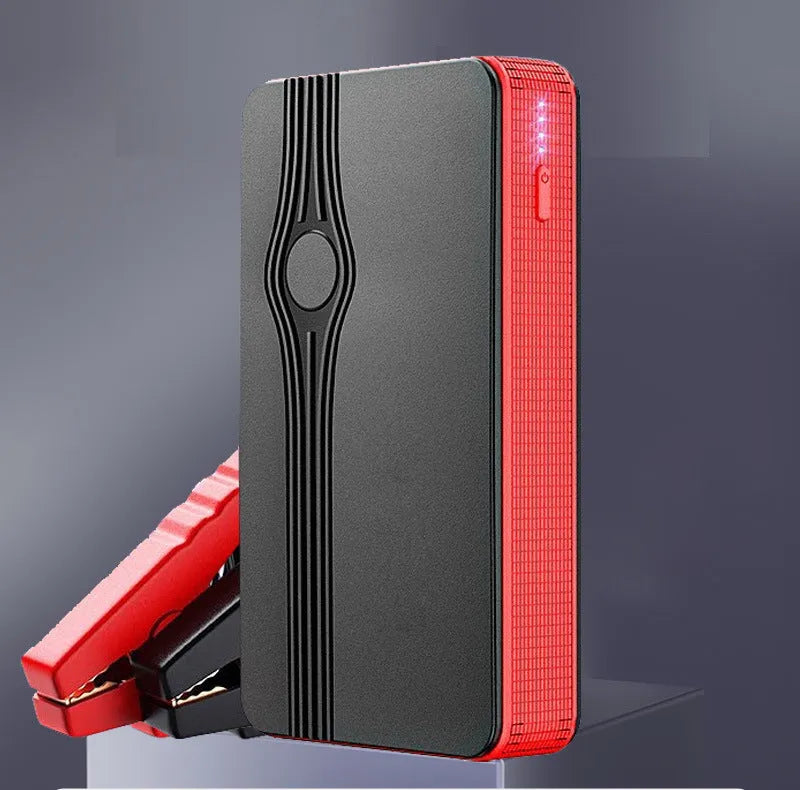 Red K4-E automobile emergency jump starter power supply unit with a USB cable on a table.