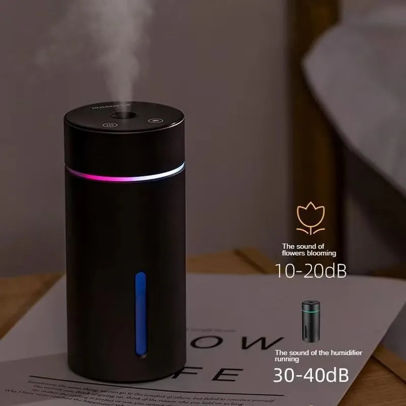 Compact aluminium car humidifier diffuser with colourful light and USB cable on a desk.