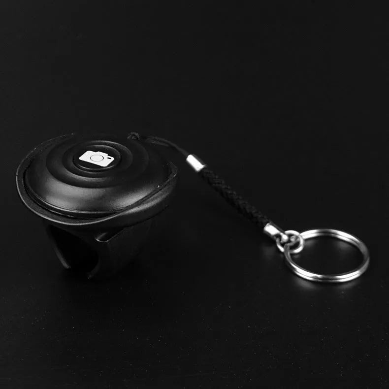 Black Bluetooth selfie remote with a clip-style snap grip for handheld or mounted use.