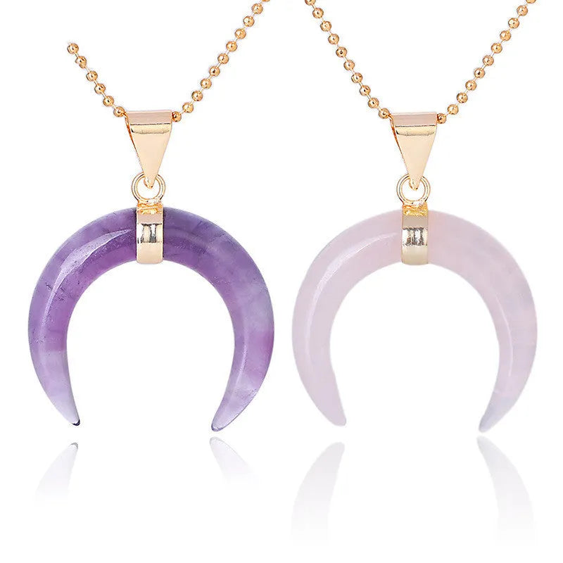 Close-up of a moon-shaped pink natural stone pendant on a metallic chain necklace.