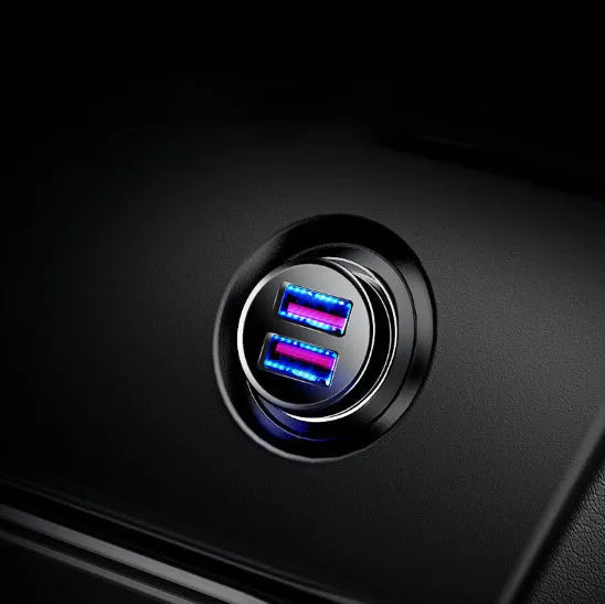 Black aluminium alloy dual USB smart car charger plugged into a 12V car socket.