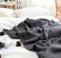 Nordic fringed knit ball acrylic blanket in beige colour, measuring 130 by 170 centimetres.