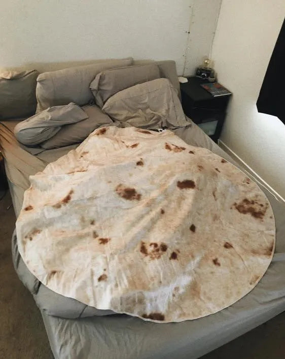 Round coral fleece burrito blanket with food print, shown in a folded pile.