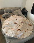 Round coral fleece burrito blanket with food print, shown in a folded pile.