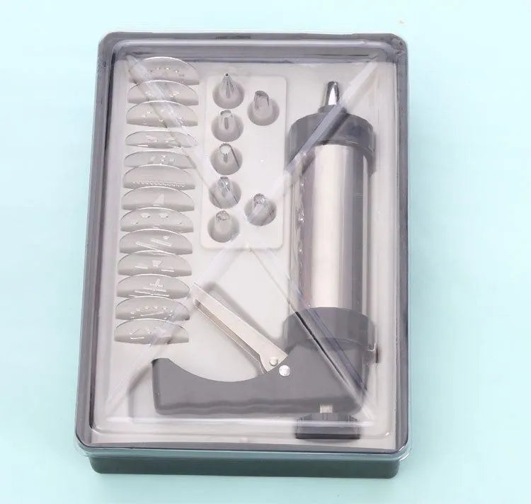 Stainless steel biscuit press gun with set of cookie moulds and piping nozzles on baking tray