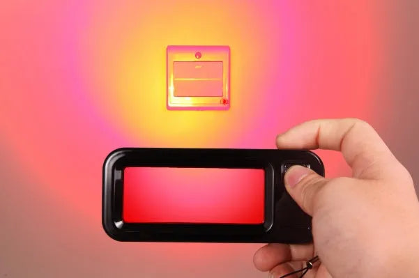 Small red reverse camera detector unit with a scanner window for detecting hidden surveillance lenses.