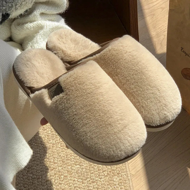 A pair of solid-colour plush winter slippers with a non-slip PVC sole on a wooden floor.