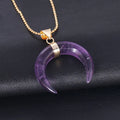 Close-up of a moon-shaped pink natural stone pendant on a metallic chain necklace.