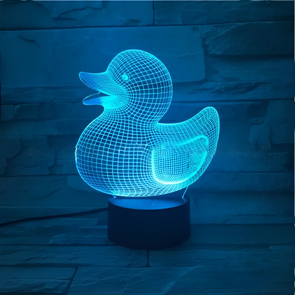 Little yellow duck 3D night light showing colourful LED illumination on a table with remote control.