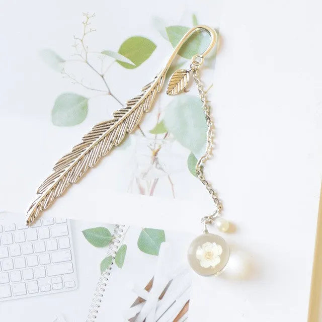 Flat metal bookmark with a dried flower inside, showing colour options like blue starry sky and dandelion.