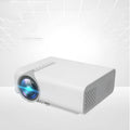 Black portable HD projector with LED lens on a table showing a movie projected on a wall