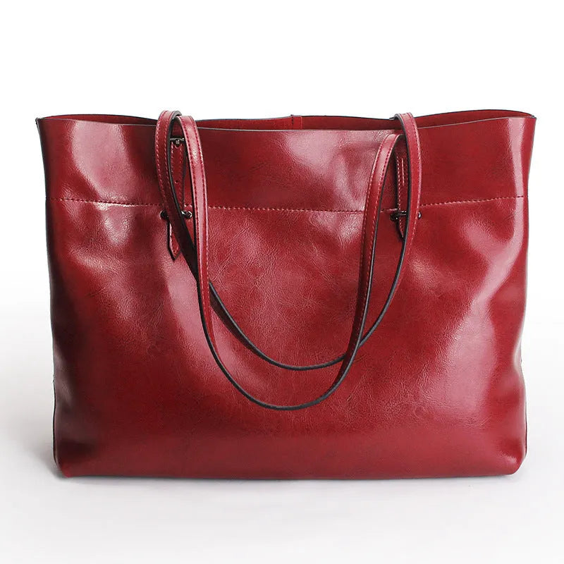 Brown leather cross-body handbag with a horizontal design showing two main compartments and a long strap.