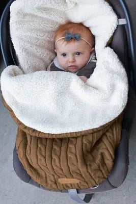 Envelope-style baby stroller sleeping bag in beige colour with thick filling, shown next to a pram.