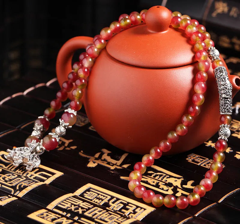 Handmade bracelet with geometric watermelon crystal beads and a Chinese knot closure.