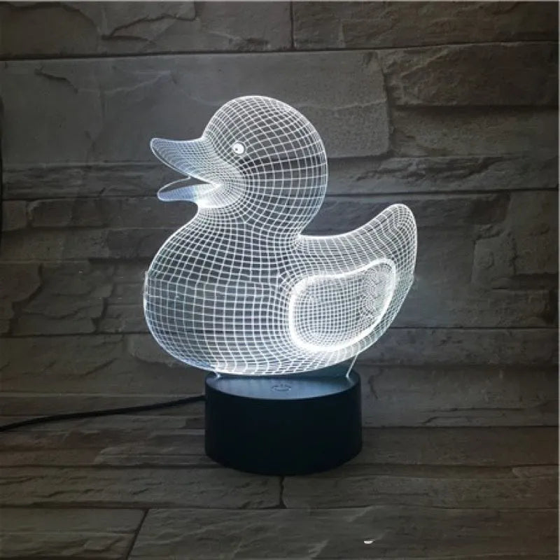 Little yellow duck 3D night light showing colourful LED illumination on a table with remote control.