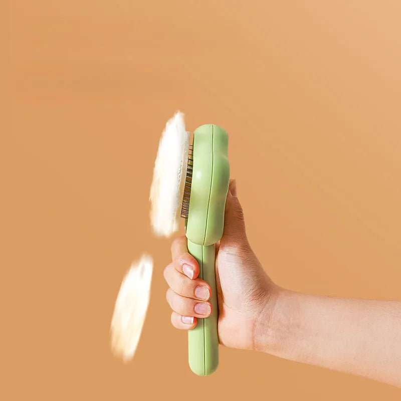 Green and yellow self-cleaning stainless steel cat comb with needle teeth on a wooden table.