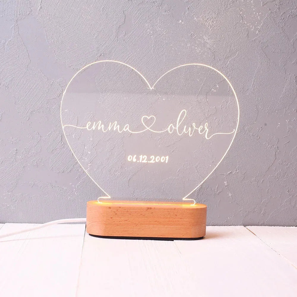 Custom transparent acrylic night light with personalised text, lit by LED, on a bedside table.
