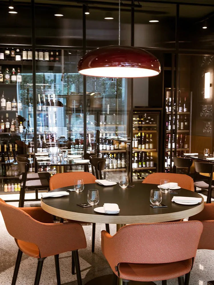 Danish-style iron pendant lamp with adjustable cord above a restaurant table.