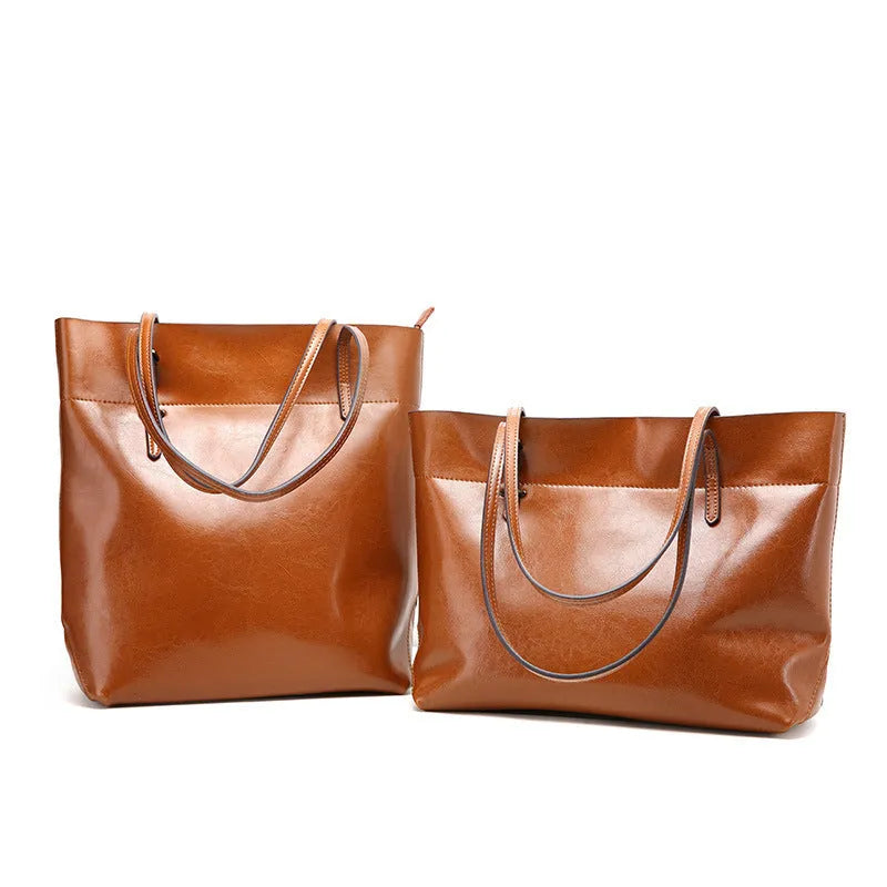 Brown leather cross-body handbag with a horizontal design showing two main compartments and a long strap.