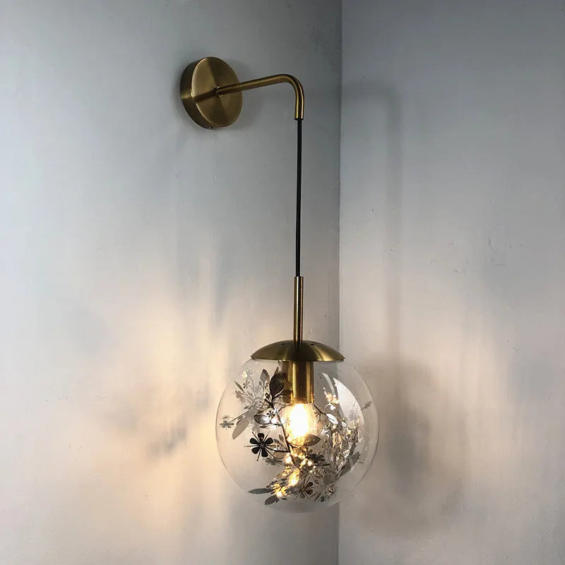 Modern simple glass bedside wall lamp in silver or gold finish on a white wall.