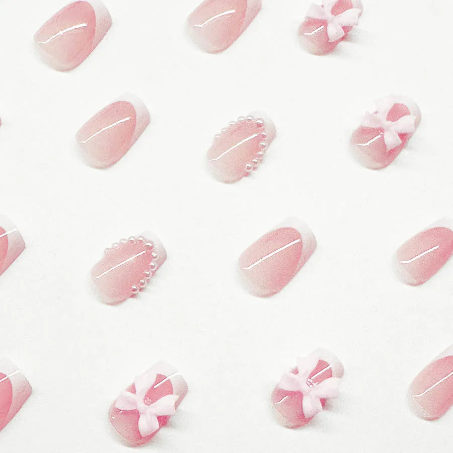 Short square French manicure artificial nails with white bow and floral patterns.