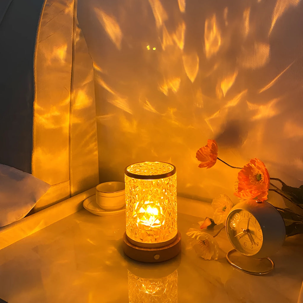 Compact rotating water ripple effect LED night light with solid wood base on a bedside table.