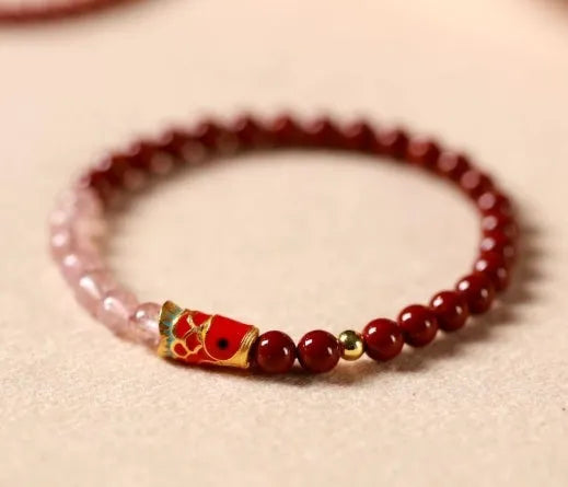 Hand-woven purple gold sand and strawberry quartz koi bracelet with crystal and pearl beads on a light background.