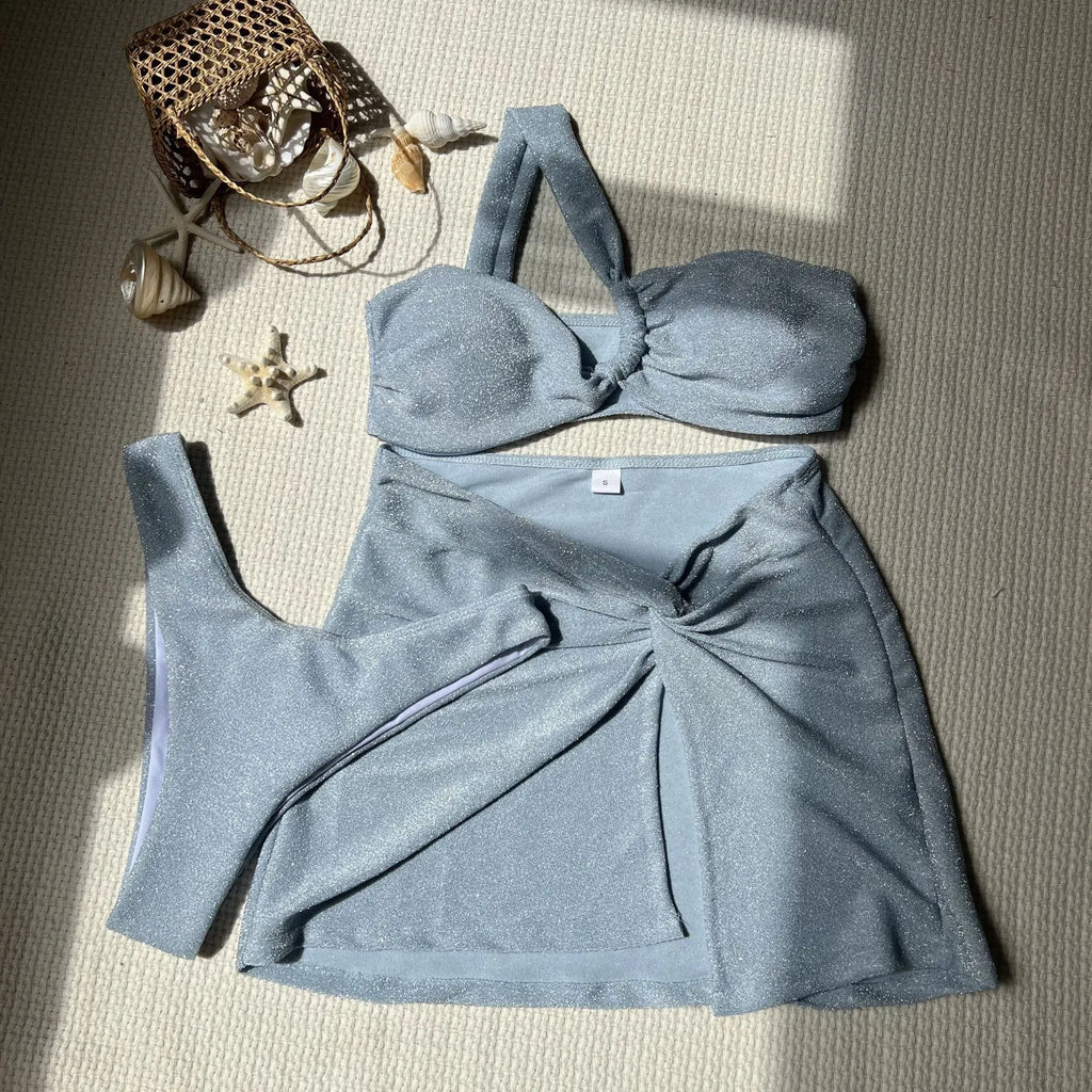 Women's light green one-shoulder swimsuit top with matching skirt and pants.