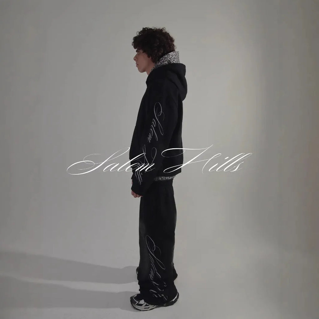 Men's black and white punk print pullover hoodie and pants tracksuit set on a hanger.