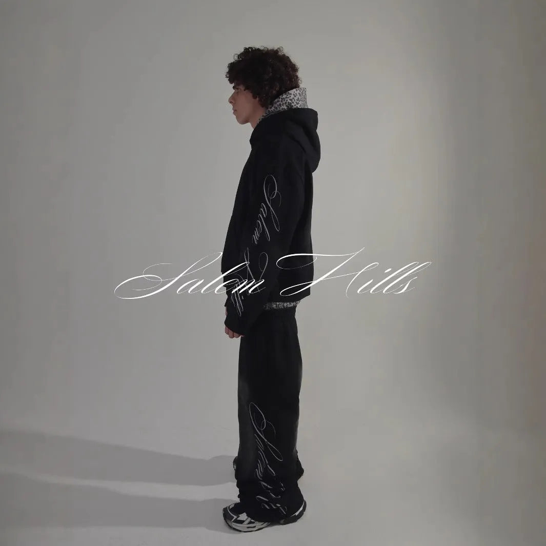Men's black and white punk print pullover hoodie and pants tracksuit set on a hanger.