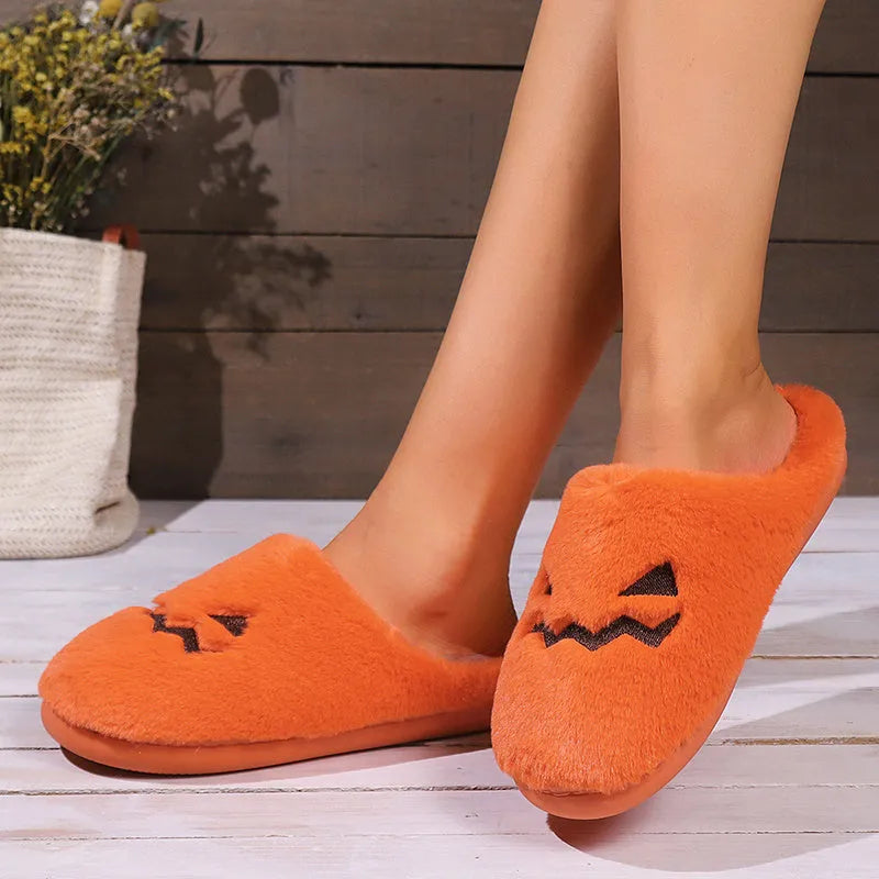 Orange Halloween pumpkin-themed plush slippers with a coral velvet upper and flat heel.