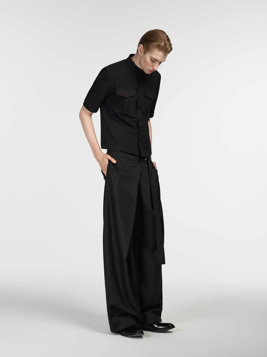 Black straight-leg trousers with a single pleat and adjustable waistband on a hanger.