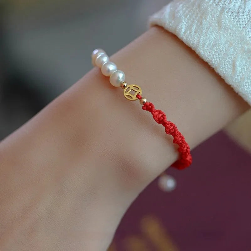 Women's pearl bracelet with gold-plated fu charm on braided red rope
