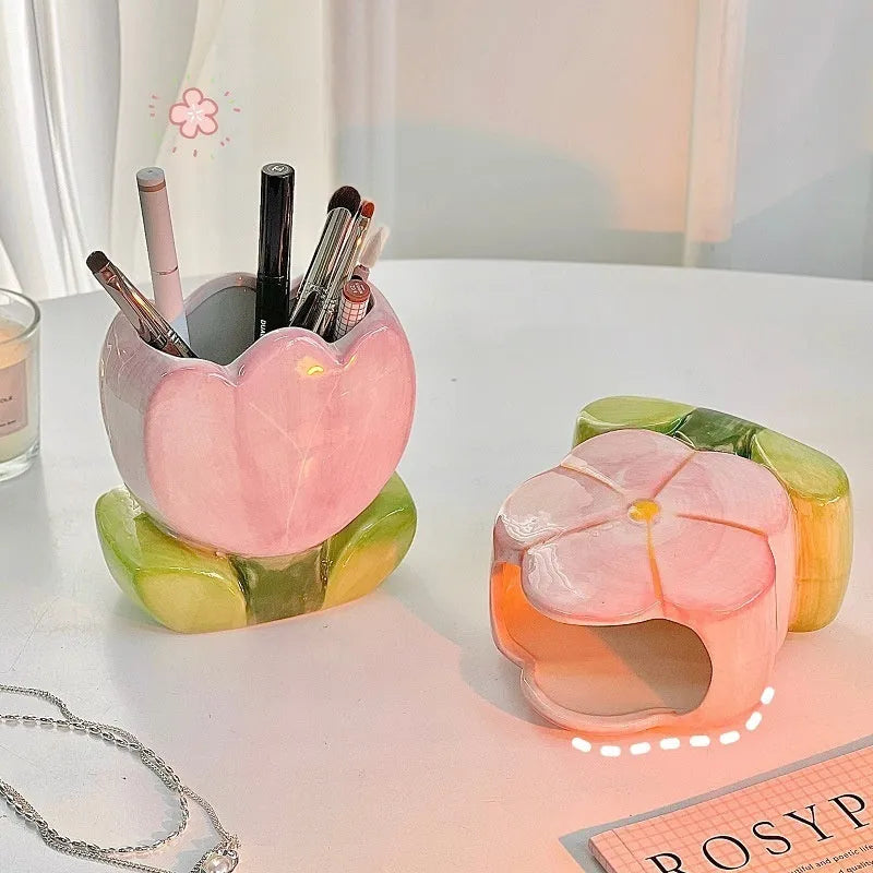 Ceramic pen holder box with floral decoration on a desk, holding pens.