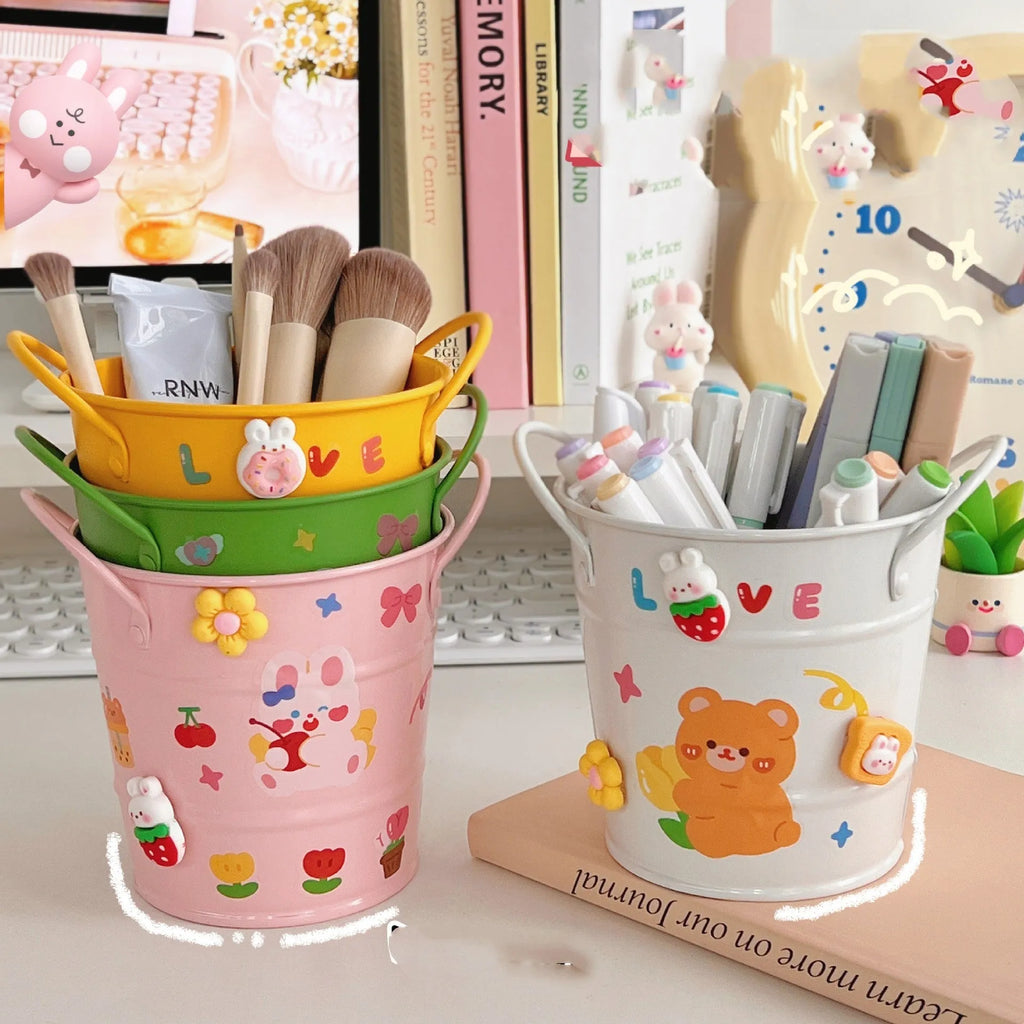 Round metal pen holder in a choice of colours including green, pink, and red on a wooden desk