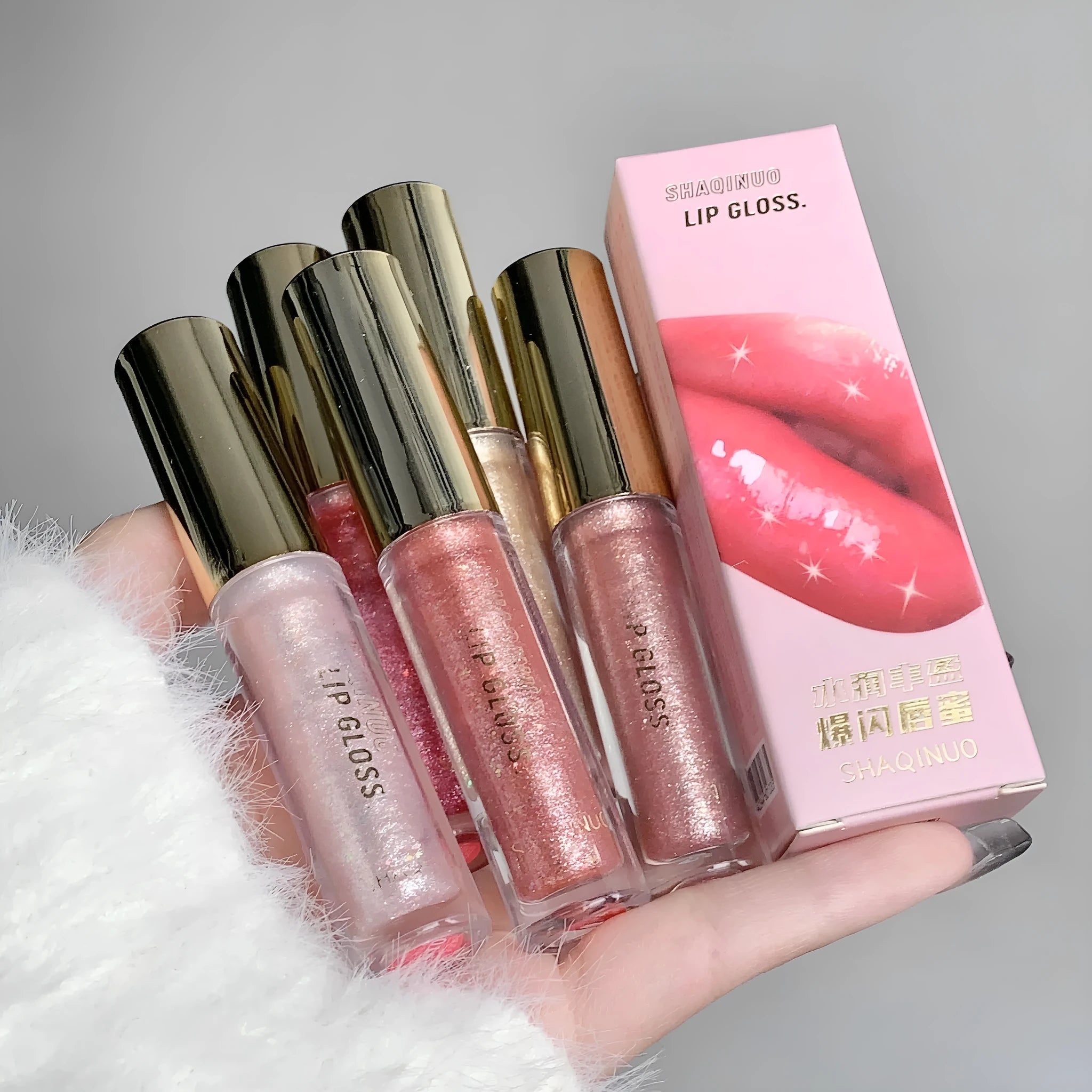 Shanuo Flash Lip Gloss tube showing five colour shades: cherry blossom pink, gold flash, peach, purple, and berry red.