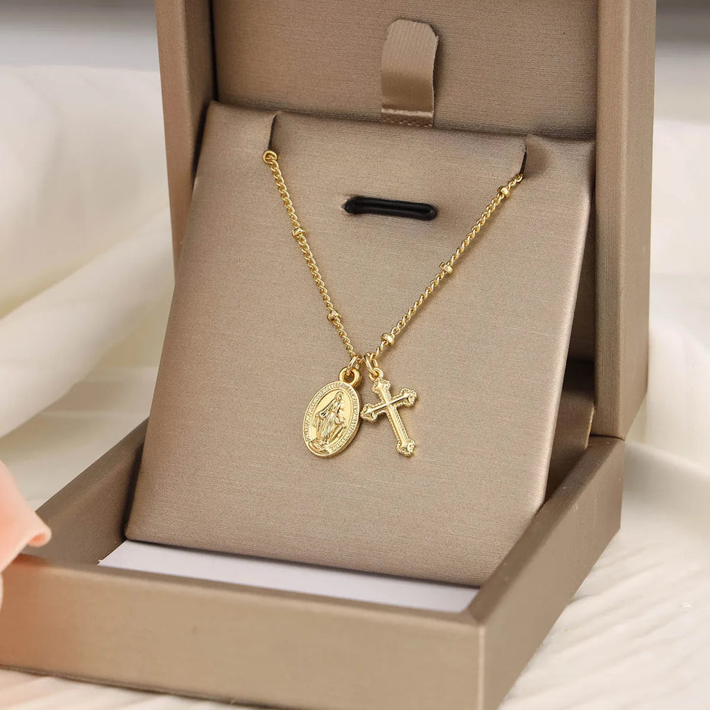 Gold geometric cross pendant necklace with Virgin Mary centre on a model.