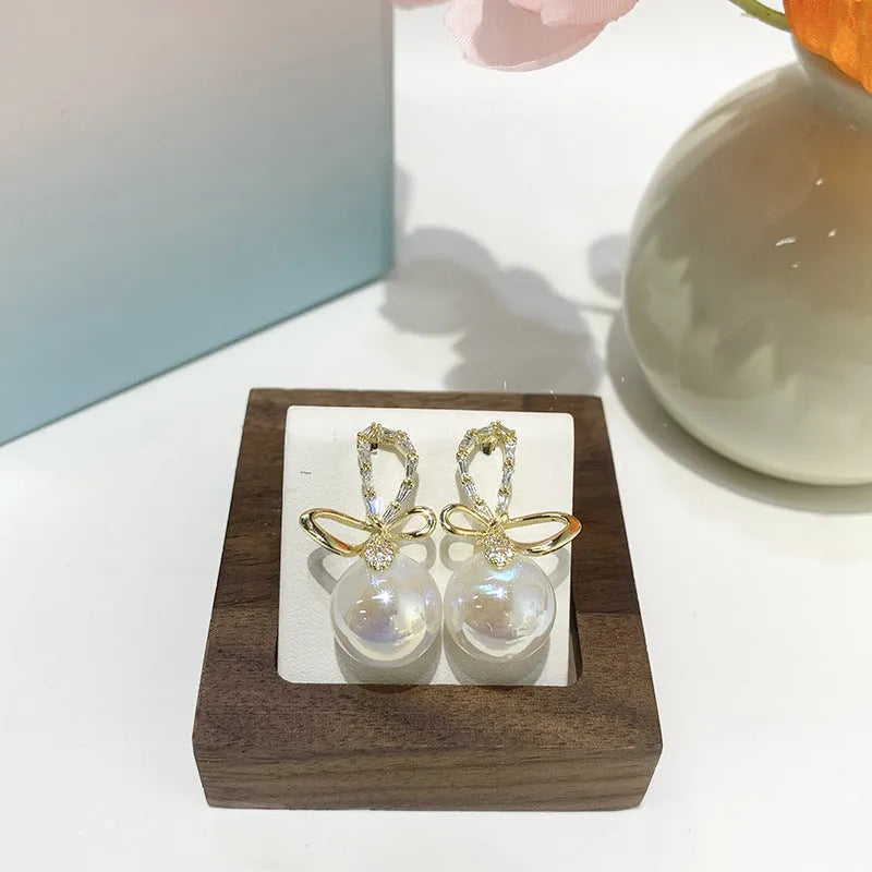 Pair of minimally designed gold tone drop earrings with single faux pearl