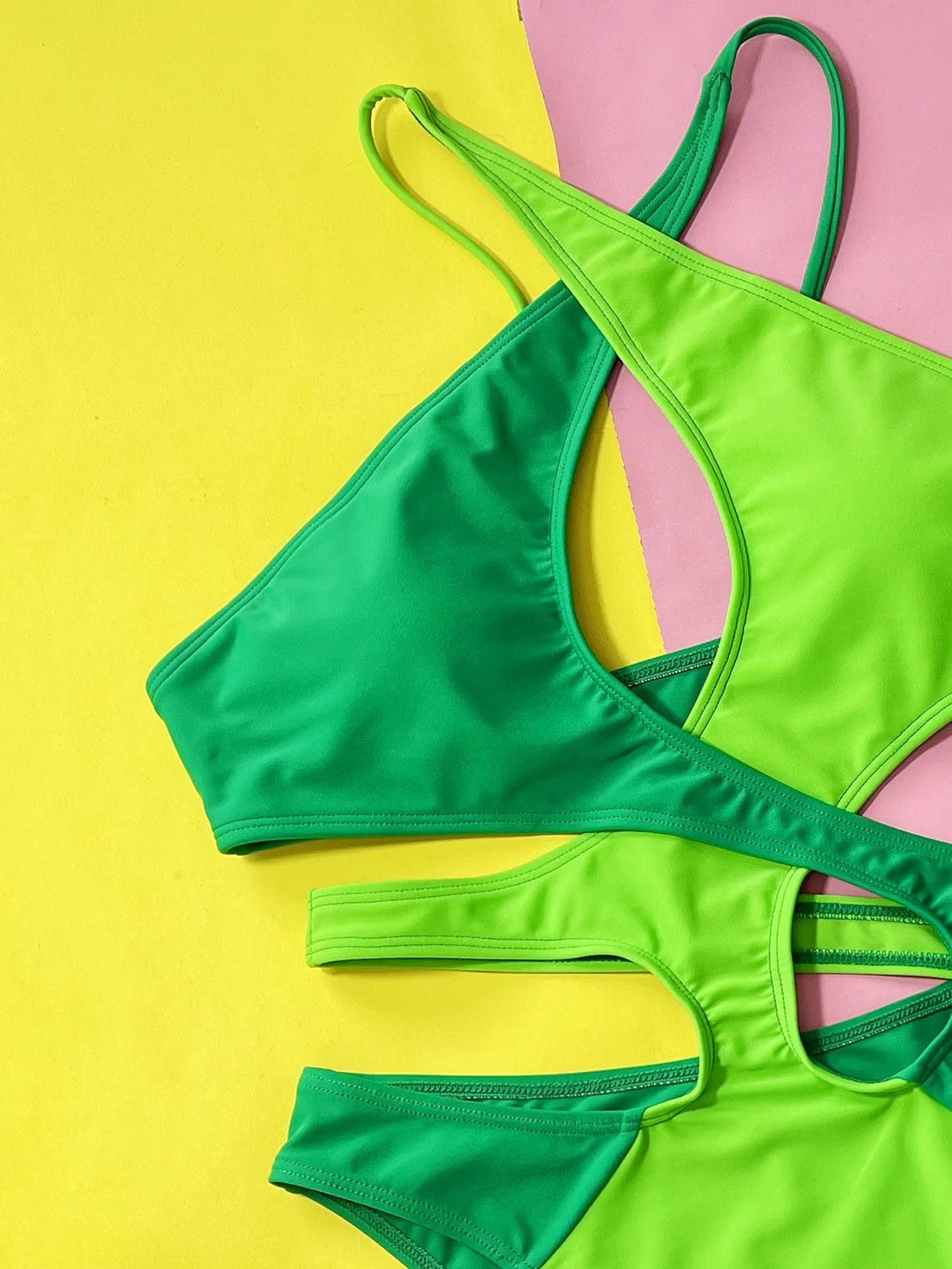 Green women's one-piece swimsuit with a contrast hollow design on a mannequin.