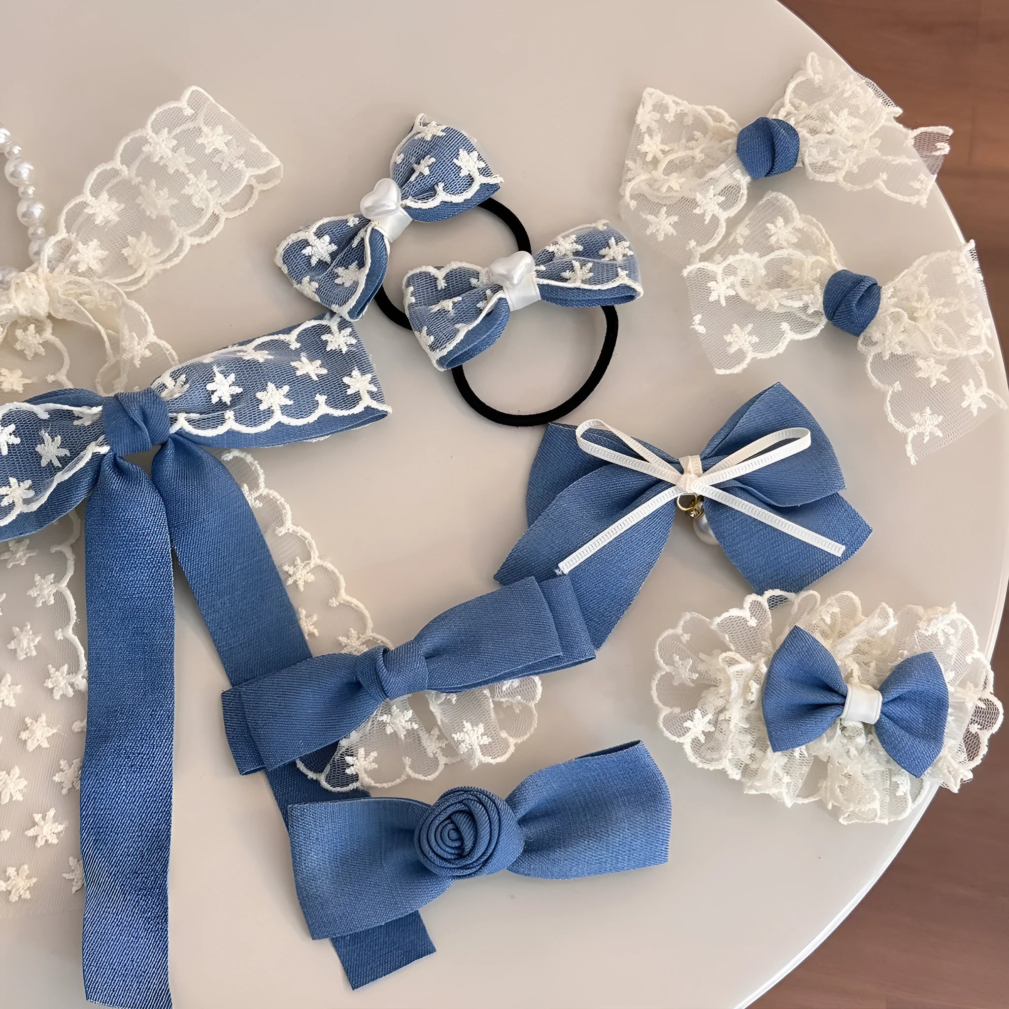 A women's hair clip barrette with a soft blue cloth bow and lace decoration on a plastic clip.