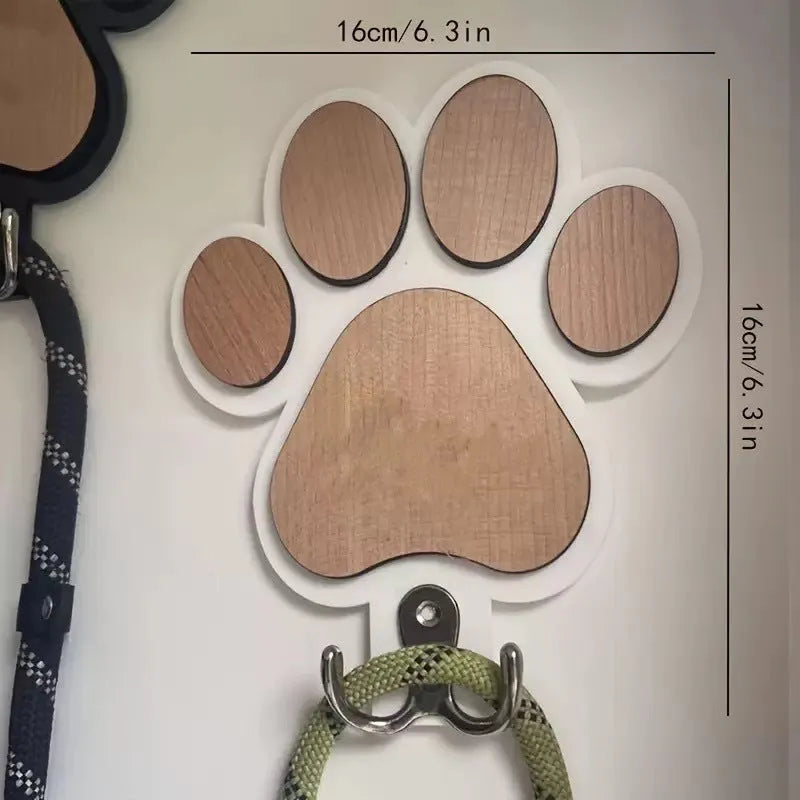 Black wooden wall hook with raised paw print design against a white wall.